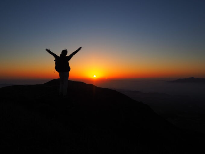 久住山山頂から朝日を眺める男性